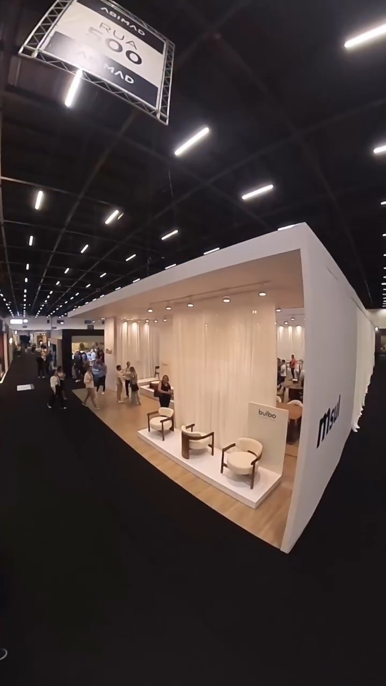 Stand da MSul na ABMAD, com estrutura branca, área de reunião e exposição de móveis