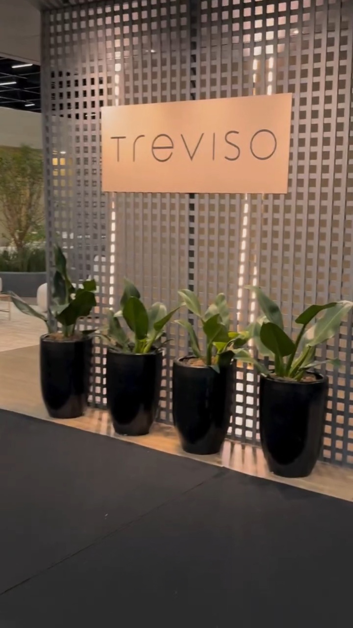 Detalhe do stand Treviso na ABMAD, com painel vazado e vasos de plantas